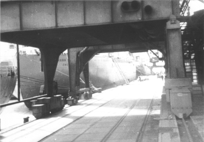 Photo mit Blick durch einen Schiffskran auf das Autoschiff MS JOHANN SCHULTE. Das Schiff wird im Emder Hafen mit VW-Käfern beladen, die in die USA exportiert werden sollen. 1967.