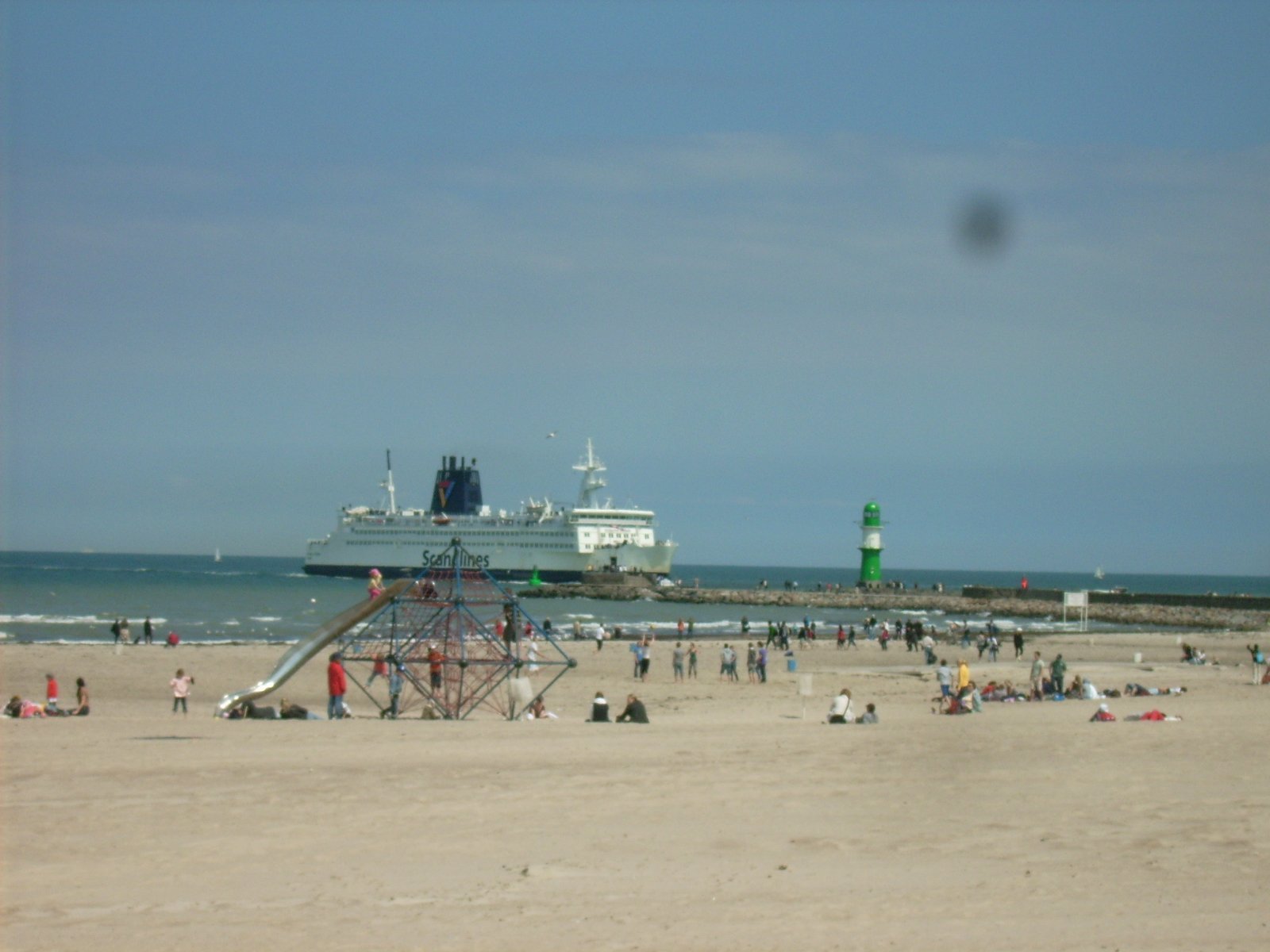 Farbphoto: Blick auf den Sandstrand in Warnemünde und auf eine aus der Ostsee in den Hafen von Warnemünde/Rostock hereinfahrende Skandinavienfähre. Juni 2009. Photograph: Bernd Paepcke.